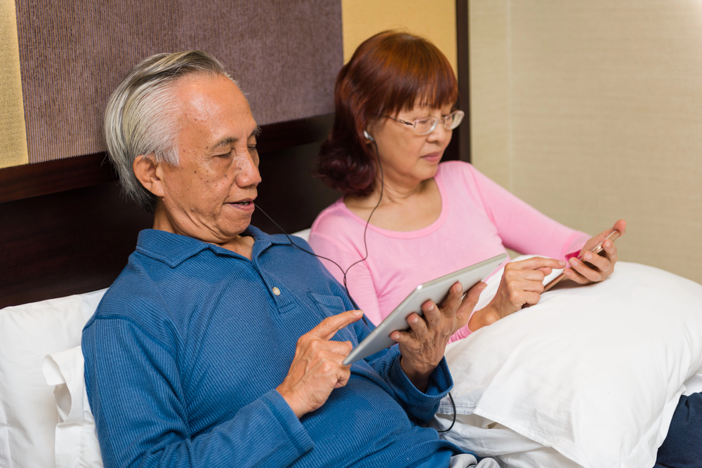 A couple is reading an ebook on a tablet and listening to an audiobook